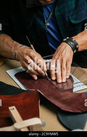 Immagine ritagliata di un maschio di calzolaio rendendo il design per un nuovo scarpe a la sua officina. Vera pelle borsetta master al lavoro in officina locale. Co fatti a mano Foto Stock