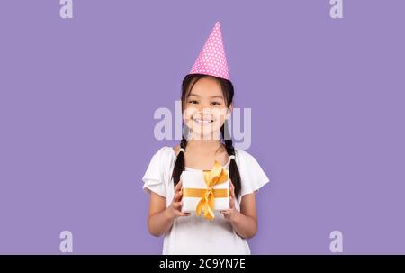 Happy Asian Girl Holding scatola regalo compleanno in posa in studio Foto Stock