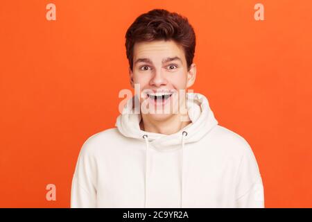 Giovanotto estremamente felice, con occhi e bocca molto aperti, sorridendo sinceramente guardando la macchina fotografica, soddisfatto della buona vita. Studio interno girato isolato o Foto Stock