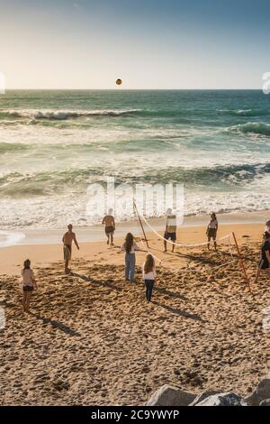 Un gruppo di vacanzieri che gioca una partita di pallavolo sulla spiaggia di Fistral a Newquay in Cornovaglia. Foto Stock