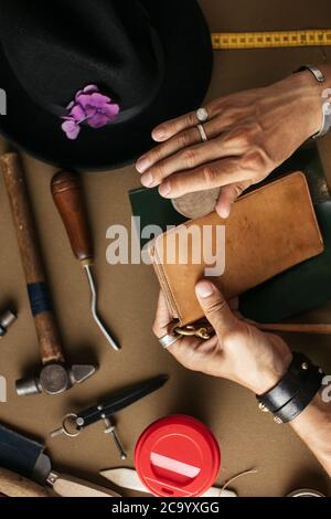 Procedimento dettagliato della pelletteria artigiano rendendo personalizzata in portafoglio in vera pelle in officina. Concetto di fatti a mano. Artigianali in pelle. Small busines Foto Stock