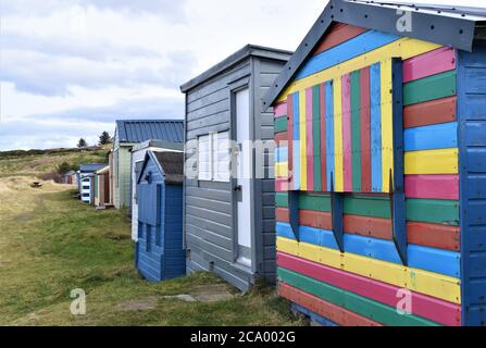 Una fila di capanne dipinte sulla spiaggia di Hopeman sul Moray Firth a Moray, Scozia Foto Stock