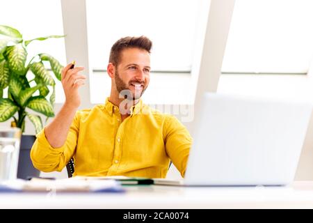 Foto di un uomo d'affari felice seduto dietro il suo laptop e che ha discussione e riunione online in videochiamata. Foto Stock