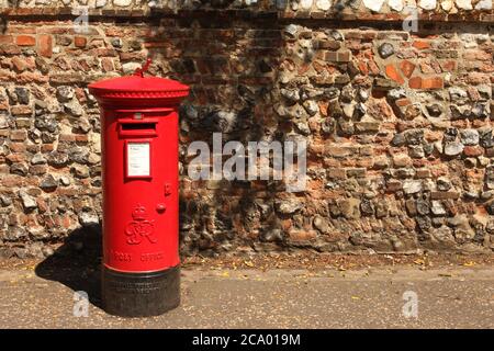 Casella postale rossa British Royal Mail di fronte al muro di pietra focaia Foto Stock