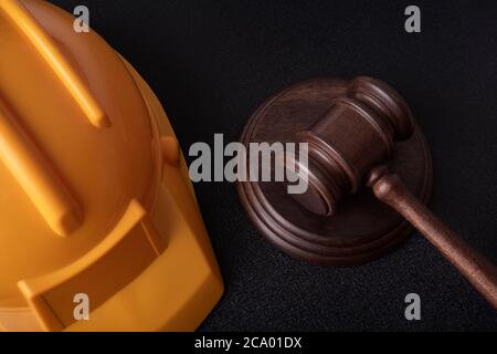 Elmetto di sicurezza giallo e Giudice Gavel. Legge sulla costruzione. Primo piano. Foto Stock
