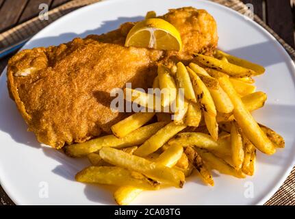 Pesce e patatine di eglefino o cena a base di pesce sul piatto al sole estivo con limone, Scozia, Regno Unito Foto Stock