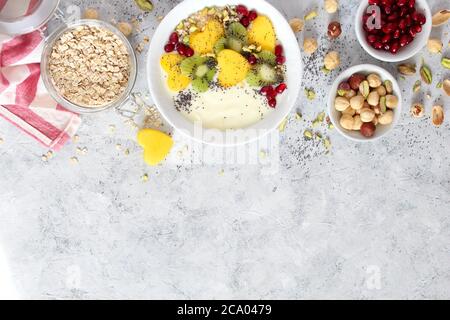 Colazione salutare con yogurt, muesli, frutta fresca e noci su sfondo chiaro. Vista dall'alto con spazio per la copia. Foto Stock