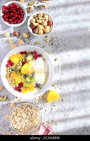 Colazione salutare con yogurt, muesli, frutta fresca e noci su sfondo chiaro. Vista dall'alto con spazio per la copia. Foto Stock