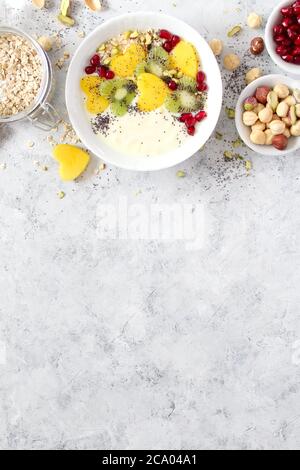 Colazione salutare con yogurt, muesli, frutta fresca e noci su sfondo chiaro. Vista dall'alto con spazio per la copia. Foto Stock