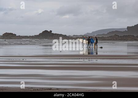 surfers su una spiaggia della cornovaglia Foto Stock