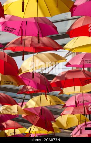 Una grande collezione di ombrelli rossi e gialli appesi al mercato di Camden creando un piacevole motivo. Londra, Inghilterra, Regno Unito Foto Stock