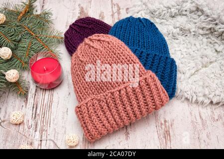 Tre cappelli. Blu, corallo e viola. Ramificazione di abete rosso, ghirlanda e candela. Sfondo di legno. Il concetto di Capodanno. Foto Stock