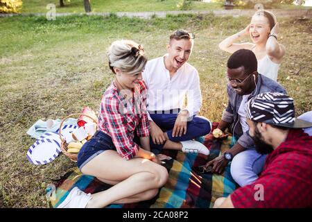 amicizia, tempo libero e tecnologia concept-gruppo di amici happy corsa mista duverse scaricare selfie foto sui social media utilizzando smartphone mentre chil Foto Stock