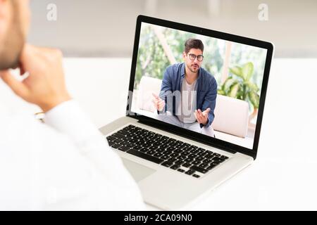 Un'immagine di un uomo d'affari irriconoscibile seduto dietro il suo laptop e che ha avuto discussioni e incontri online in videochiamata. Foto Stock
