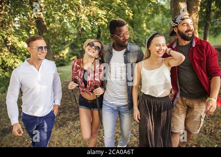 Giovane pilota BMX in compagnia dei suoi amici multietnici che camminano per divertendosi al parco cittadino Foto Stock