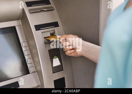 Primo piano della mano femminile che inserisce la carta di credito nella macchina ATM Foto Stock