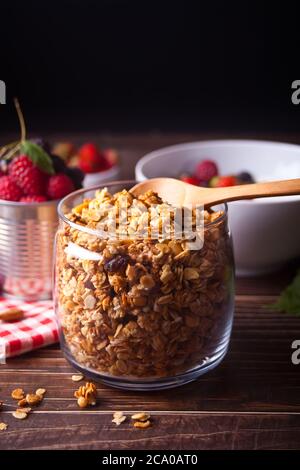 Cereali muesli di avena sani in un vaso con frutti di bosco freschi sullo sfondo. Foto Stock