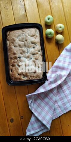 torta di mele, mele verdi e un asciugamano su tavola di legno piatto. L'immagine contiene spazio per la copia Foto Stock