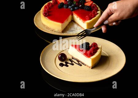 una fetta di torta di frutta rossa su un piatto di ceramica fotografato su sfondo nero Foto Stock