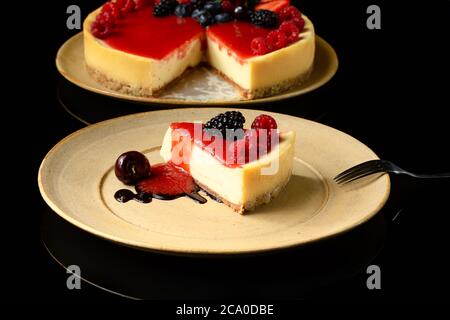 una fetta di torta di frutta rossa su un piatto di ceramica fotografato su sfondo nero Foto Stock