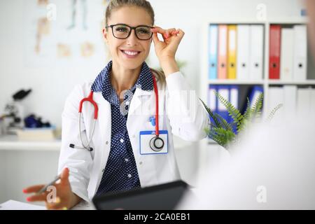 Donna medico con occhiali sorridenti sul posto di lavoro in ufficio medico Foto Stock