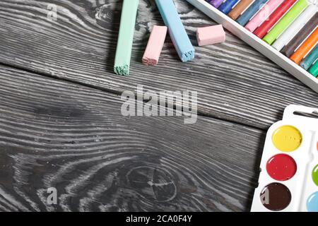 Gesso di diversi colori, acquerelli e pastelli per il disegno. Su tavole di pino dipinte di nero. Foto Stock