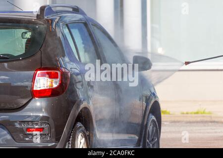 Lavare l'auto con una pistola con getto d'acqua ad alta pressione Foto Stock