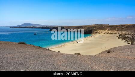 Spiaggia di Playa Mujeres con Oceano Atlantico e paesaggio arido circostante sulla costa Papagayo di Playa Blanca, Lanzarote, Isole Canarie, Spagna. Foto Stock