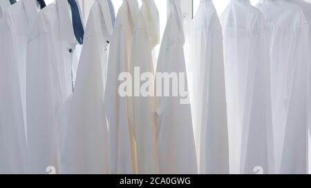 le camicie bianche da uomo sono appese sulle spalle dell'armadio Foto Stock