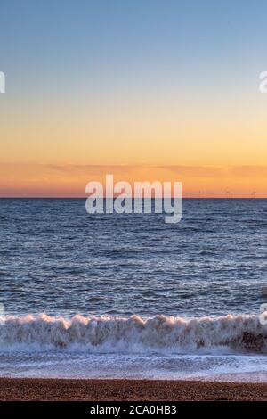 Tramonto a Brighton Beach, con un parco eolico offshore all'orizzonte Foto Stock
