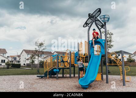 Ragazzi che giocano su una struttura di gioco in un parco giochi nella nuvolosa giornata estiva. Foto Stock