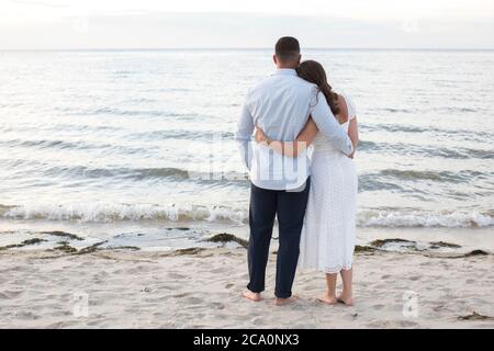 coppia romantica da dietro guardando l'oceano braccio in braccio Foto Stock