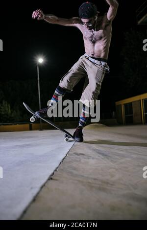 giovane uomo bianco che salta sul suo skateboard Foto Stock