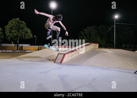 giovane uomo bianco che salta sul suo skateboard Foto Stock