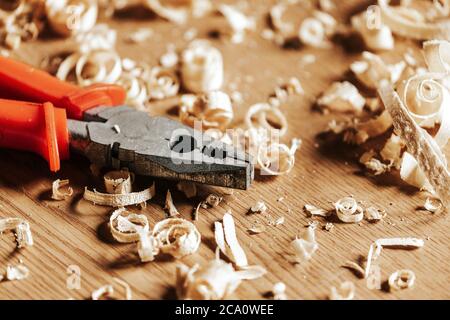 Una pinza arancione è su un tavolo di legno, accanto ad una segatura di legno in officina Foto Stock