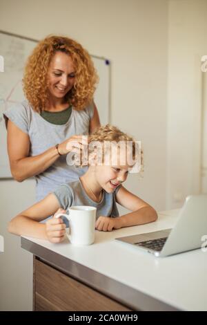 Sorridendo attraente tutor caucasico femminile aiuta il suo adorabile studente a fare difficile compito in classe scolastica. Foto Stock