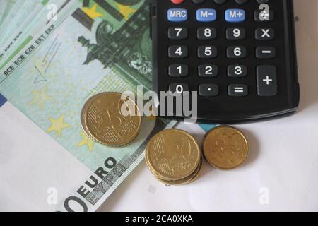 Banconote e monete in euro e calcolatrice. Concetto aziendale di conteggio di denaro Foto Stock