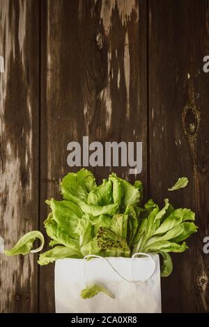 Fresco Lettuce Lleeson in una borsa di carta un tavolo di legno scuro. Insalata di Batavia Foto Stock