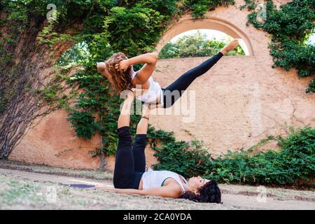 Due belle donne che fanno acroyoga nel giardino o nel parco Foto Stock