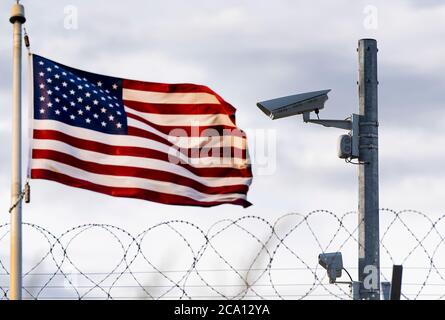 Confine USA, telecamera di sorveglianza, filo spinato e bandiera USA, immagine concettuale Foto Stock