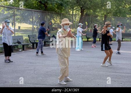 Uomini e donne di varie età ed etnie frequentano una lezione di Tai Chi al mattino indossando maschere chirurgiche e divaricatori sociali. In Queens, New York City. Foto Stock