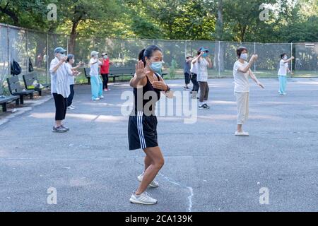 Donne di varie età ed etnie frequentano una lezione di Tai Chi al mattino che indossa maschere chirurgiche e divaricazioni sociali. In Queens, New York City. Foto Stock