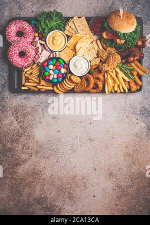 Assortimento di fast food. Concetto di cibo spazzatura. Cibo malsano per il cuore, i denti, la figura. Foto Stock