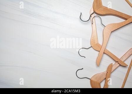 Appendiabiti in legno vuoti su sfondo in marmo bianco. Vista dall'alto, spazio di copia. Negozio di abbigliamento e concetto di sconti. Foto Stock