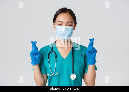 Covid-19, malattia del coronavirus, concetto degli operatori sanitari. Primo piano di speranzoso medico femminile asiatico, medico in maschera medica e guanti di gomma Foto Stock