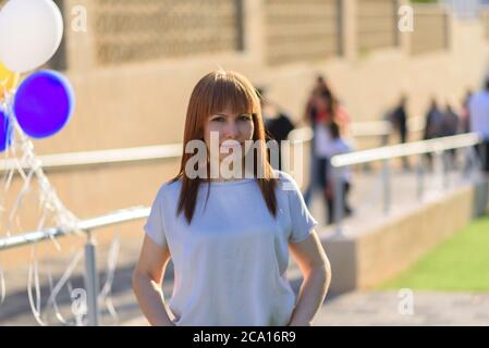 Esterno Ritratto di felice bella donna bionda di 40 anni. Attiva bella donna di mezza età sorridente amichevole e guardando in macchina fotografica in città strada. Foto Stock