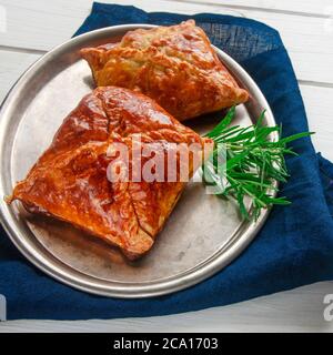 Dolci fatti in casa con carne e salsa piccante con rosmarino serviti su un vassoio di metallo su un tavolo di legno bianco Foto Stock