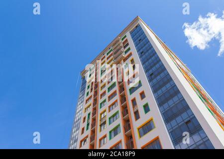 Un alto edificio contro un cielo blu. Un nuovo ed alto edificio residenziale con una facciata colorata. Foto Stock