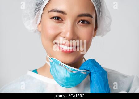 Covid-19, malattia del coronavirus, concetto degli operatori sanitari. Primo piano di speranza felice sorridente donna asiatica dottore in dispositivi di protezione personale Foto Stock