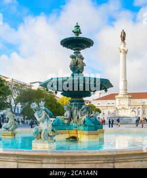 Lisbona, PORTOGALLO - 28 GENNAIO 2020: Persone alla fontana di Rossio con statue e Colonna di re Pedro IV sullo sfondo Foto Stock